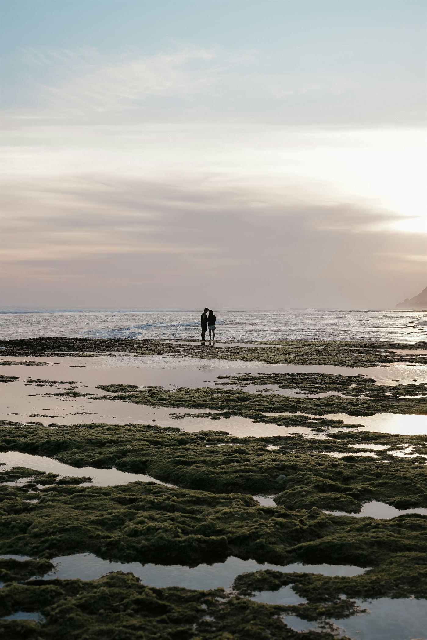 Two people standing together on a beach at dusk